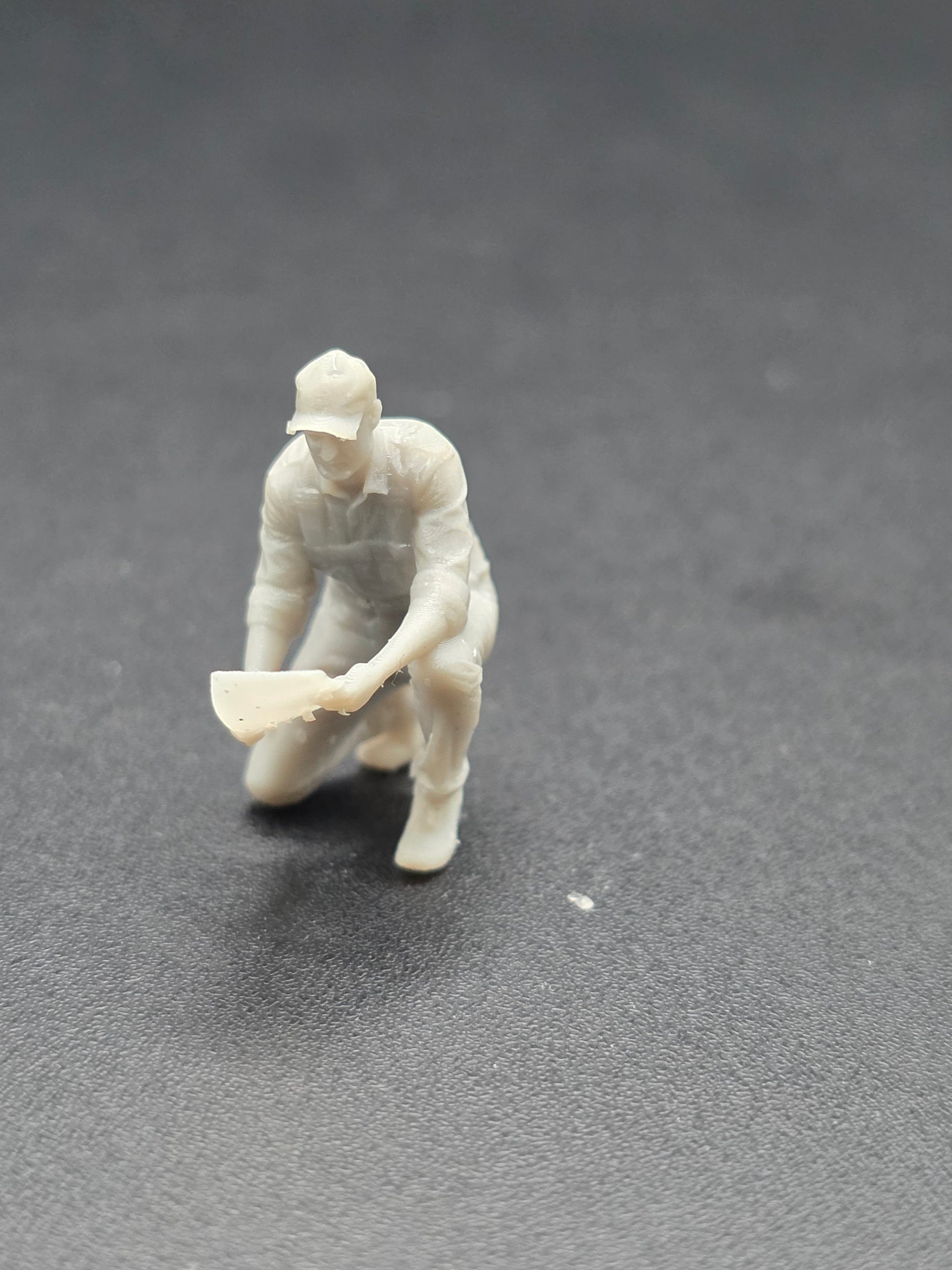 Arbeiter auf einem Knie mit einem Plan in der Hand im Maßstab 1/50