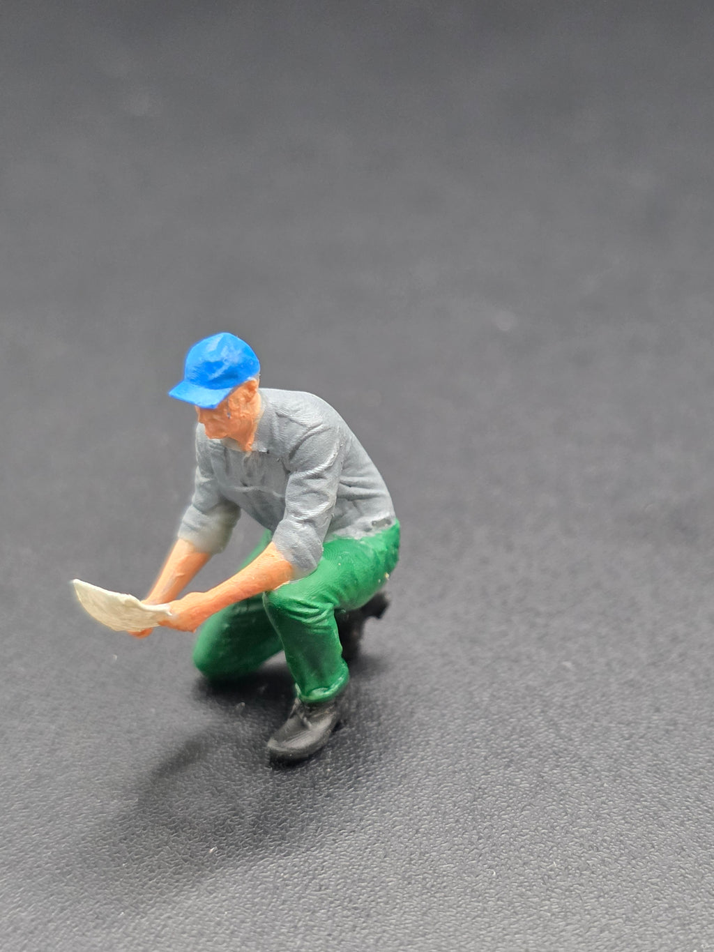 Arbeiter auf einem Knie mit einem Plan in der Hand im Maßstab 1/50